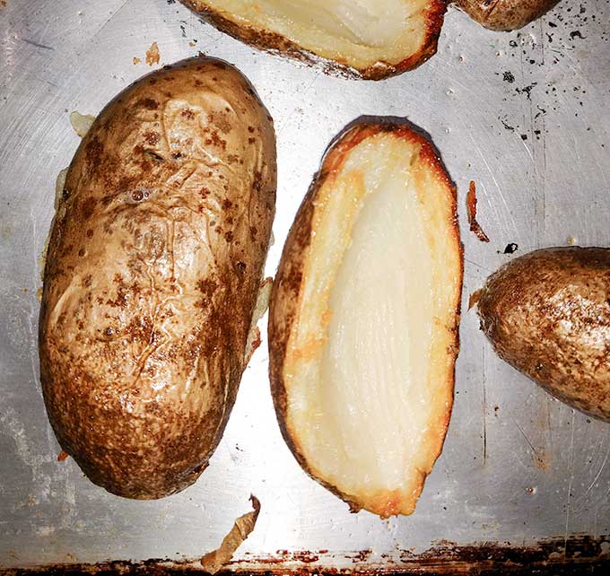 Potato skins hollowed out on baking tray