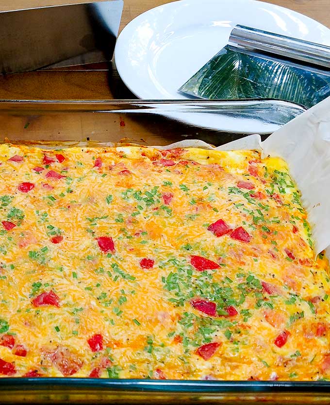 tomato and cheese frittata with parchment paper to make it easier to lift the frittata out of the baking pan
