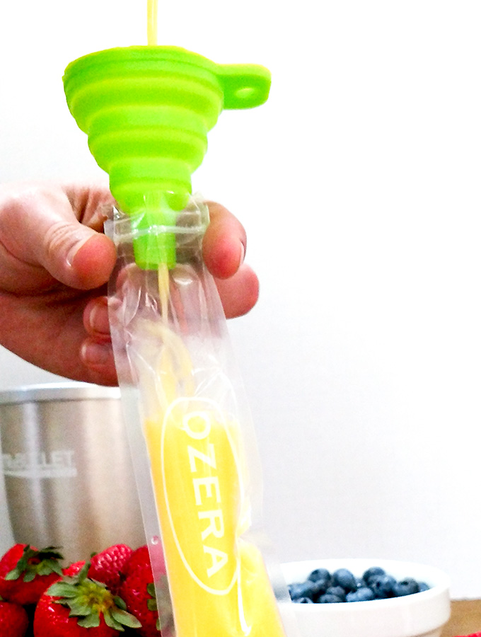 Filling mango berry popsicle tube with a funnel