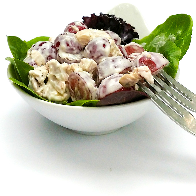 Chicken salad with grapes served over greens in a bowl