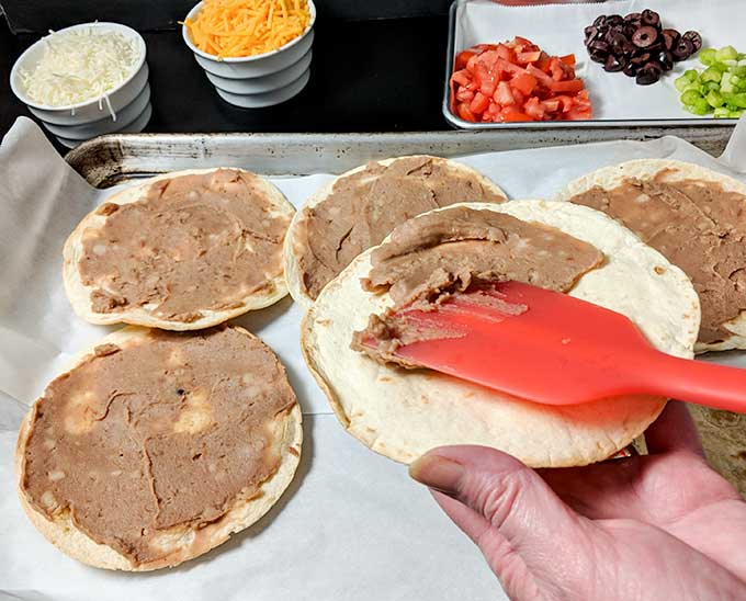 Spreading refried beans on Taco Bell Mexican Pizza recipe