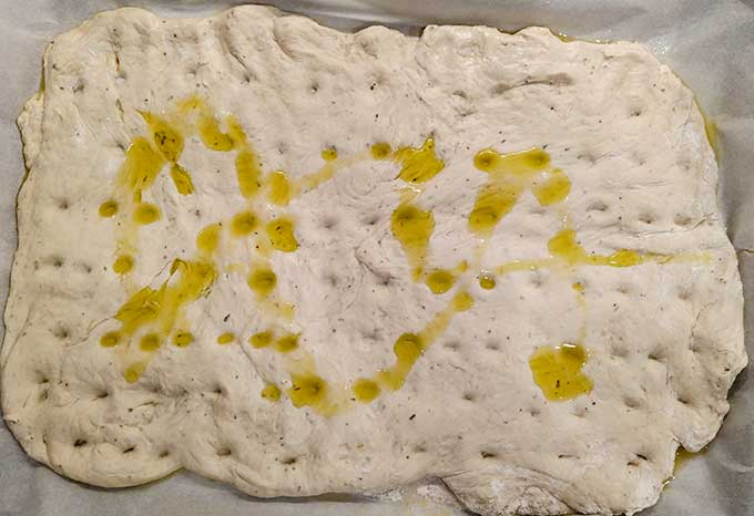 Bread machine focaccia with dimples and pools of olive oil