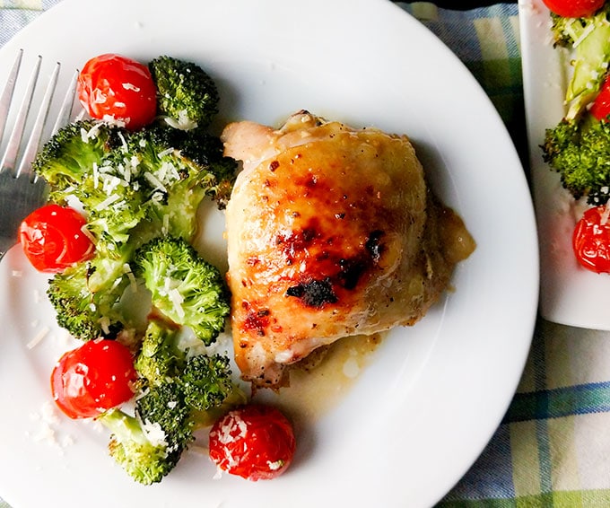 Honey dijon chicken bone in plated with broccoli and tomatoes