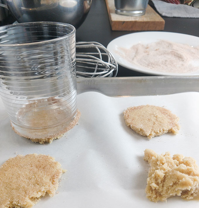 Moms Christmas cookies flattening cookie dough with a glass