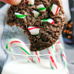 Chocolate Christmas cookies with crushed candy canes dipping in milk close up