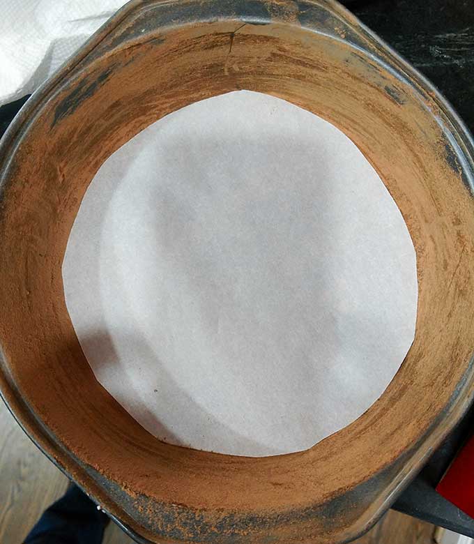 prepping cake pans with cocoa powder and parchment paper