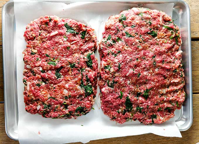 meatloaf with marinara sauce and sausage shaped on baking sheet