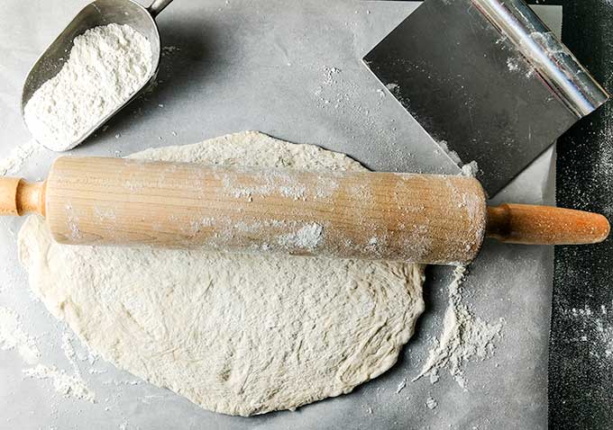 shaping pizza dough with a rolling pin