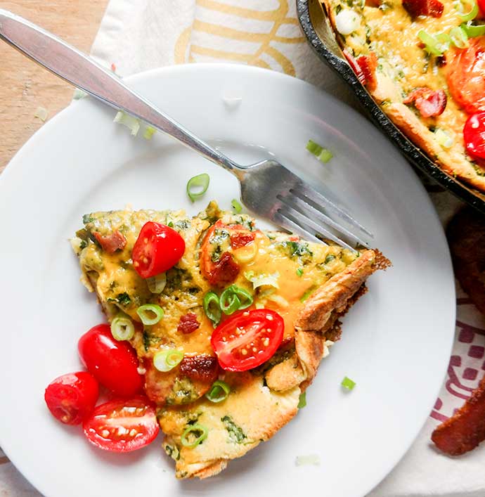 Dutch baby recipe with spinach and tomatoes sliced on plate