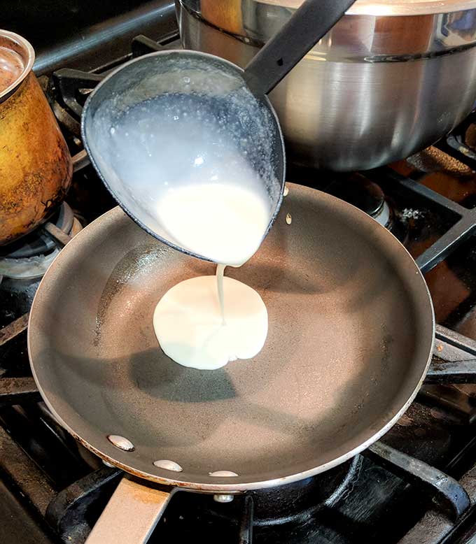 adding crepe batter to pan