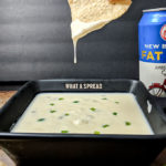 Mexican cheese dip with jalapenos with dripping cheese off chip