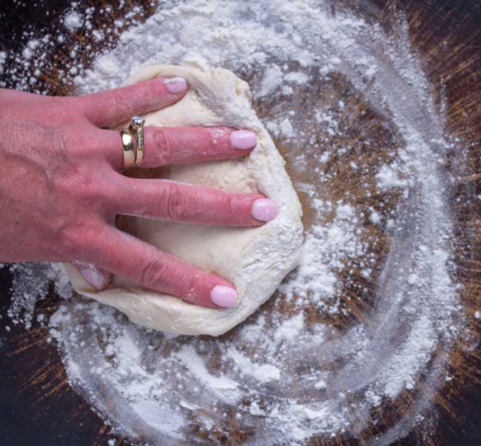 shaping pizza dough with fingers