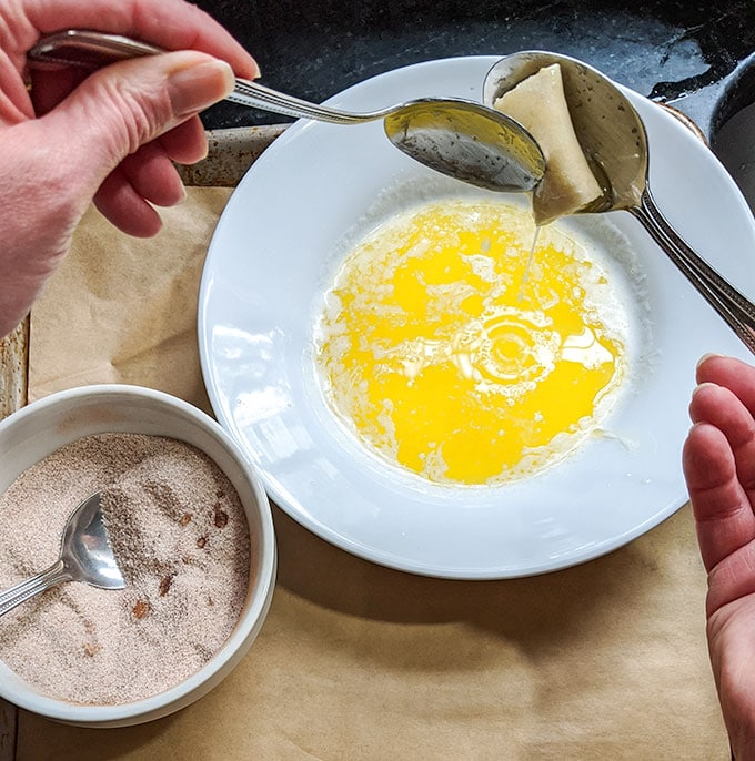 dipping cinnamon roll bites in butter
